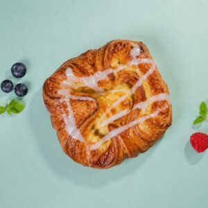Hjemmelaget wienerbrød med vaniljekrem og glasur på lys bakgrunn.